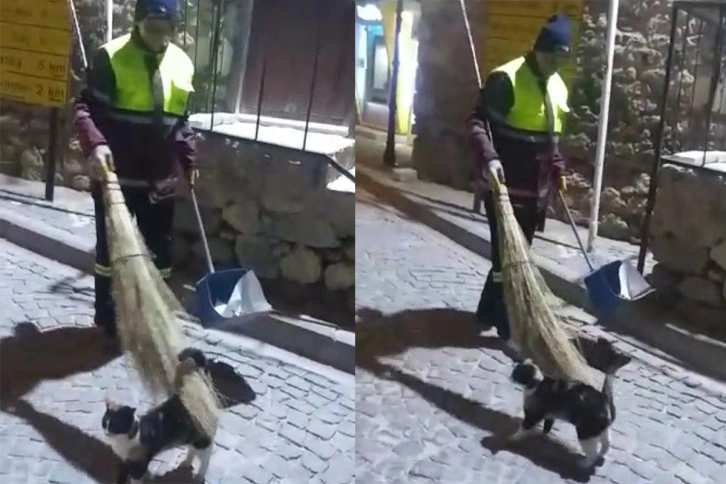 Hem çevreyi temizliyor aynı zamanda sokak kedisine süpürgesi ile masaj yapıyor
